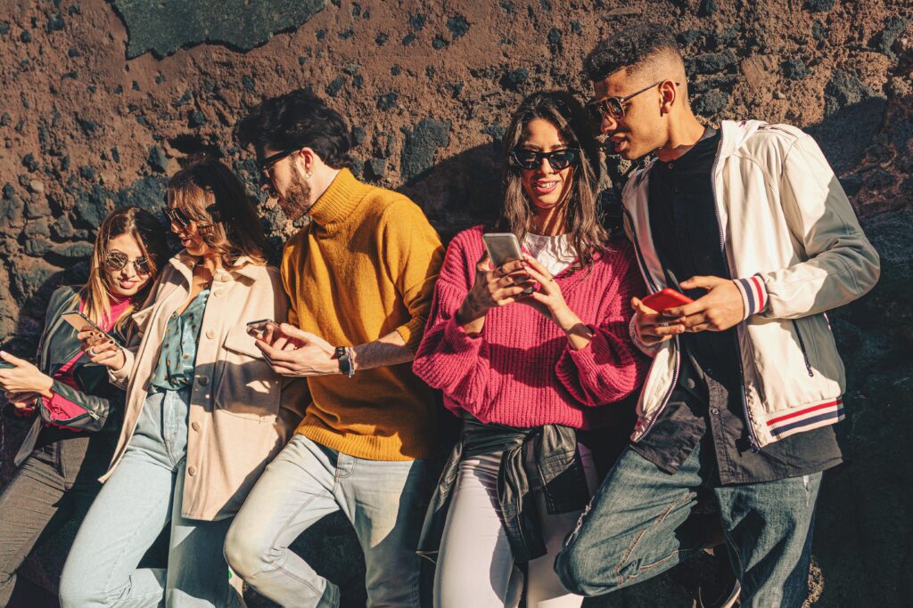 a group of 5 young people socializing and showing each other information on their smartphones